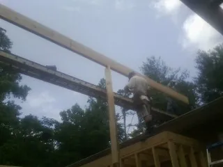 Carpenter setting a ridge beam over a new addition frame — Ice Dam Removal by Roofing Brothers in Bella Vista