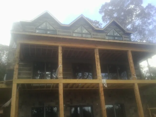 Dormers and porch framing on a large log home under construction — Roof Coating work by our crew in Bella Vista