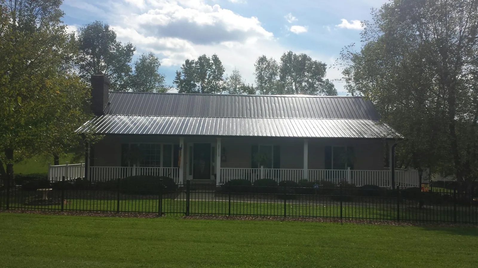 Gray metal roof on a brick ranch with a full width front porch — Gutter Guard Installation work by our crew in Bella Vista