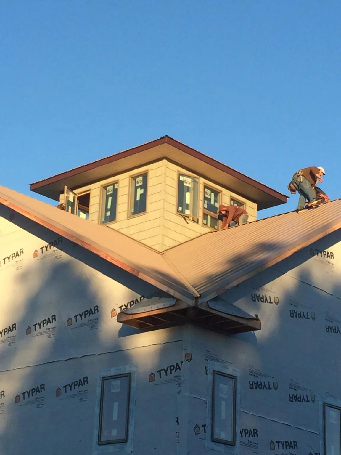 Roofers working around a rooftop cupola on a new metal roof at sunset — Roof Waterproofing in Bella Vista by Roofing Brothers